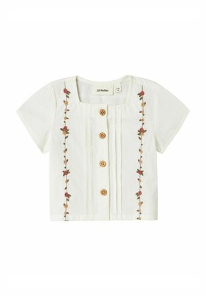 Blusa bianca a maniche corte con scollo quadrato, bottoni in legno e ricami floreali sul davanti. Tessuto leggero con pieghe.