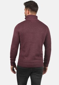 Maroonfarbener, gestrickter Pullover mit hohem Kragen, gerippten Bündchen und Saum. Verfügt über ein strukturiertes Muster und eine figurbetonte Silhouette.