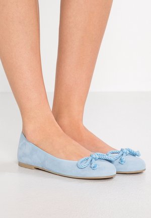 Jasnoniebieskie zamszowe baletki z okrągłym noskiem i węzłem sznurka na przodzie, z płaską, jasną podeszwą.