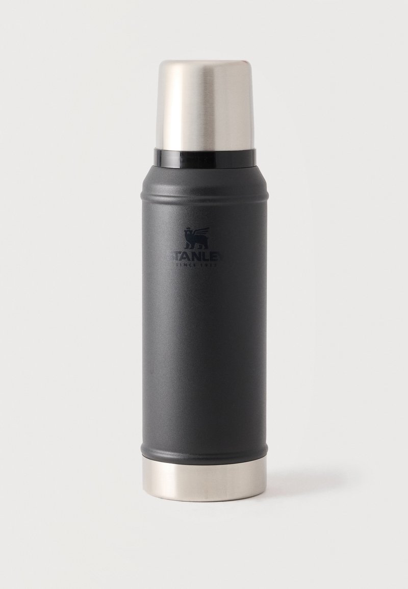 Ψηλό μαύρο και ασημί θερμός Stanley με βιδωτό καπάκι πάνω σε λευκό φόντο.