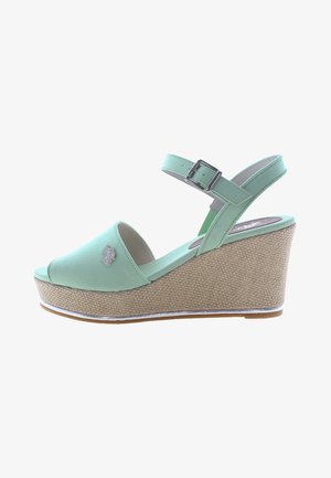 Mint green wedge sandals with a peep-toe design, adjustable ankle strap, and woven textured heel. Silver logo detail on the side.