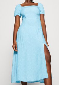 Jasnoniebieska sukienka z bufiastymi rękawami i kwadratowym dekoltem, z kwiatowym wzorem, bocznym rozcięciem i zwiewną spódnicą, wykonana z miękkiego materiału.