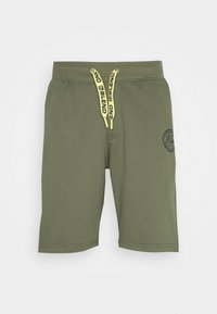 Shorts vert olive en tissu doux avec un cordon de serrage à la taille. Comprend des cordons jaunes et un logo circulaire sur le côté gauche.