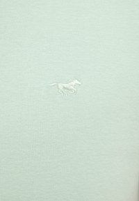 Light green cotton t-shirt featuring a small white embroidered horse logo. The fabric has a smooth, textured appearance with a fitted design.