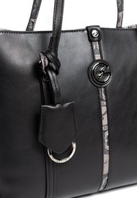 Czarna torebka z syntetycznej skóry ze srebrnymi detalami, z centralnym logo i wzorzystym paskiem akcentowym wzdłuż środka.