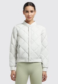 Quilted white bomber jacket with a stand collar, front zip closure, ribbed cuffs, and side pockets, paired with light green leggings.