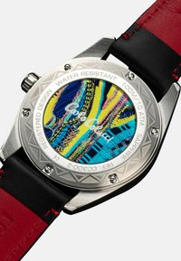 Uhrgehäuse aus Edelstahl mit einem farbenfrohen gemusterten Zifferblatt, ausgestattet mit einem schwarzen Lederarmband mit roten Akzenten. Wasserfest bis zu 100 m Tiefe.