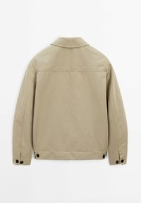 Veste beige avec col à revers, poignets à boutons et deux boutons sombres à l'ourlet. Tissu texturé et lisse. Vue de dos.