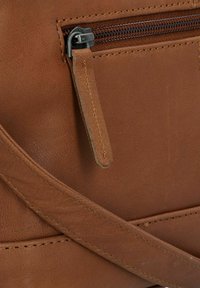 Borsa in pelle marrone con una cerniera resistente, texture liscia e una piccola tasca esterna con patta e dettagli di cucitura.