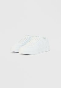 Λευκά αθλητικά παπούτσια με λείο δερμάτινο πάνω μέρος, στρογγυλή μύτη, σχέδιο με κορδόνια, ενισχυμένες λεπτομέρειες και υφασμένο λαστιχένιο πέλμα.