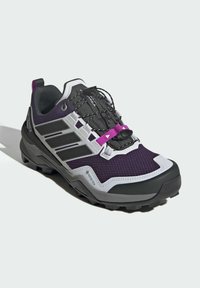 Lila und schwarze Außenschuhe aus Mesh-Gewebe, verstärkter Zehenbereich und strukturierte Sohle. Verfügt über rosafarbene Akzente und ein Schnell-Schnürsystem für einen sicheren Sitz.