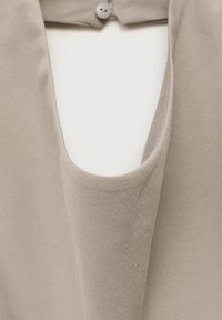 Haut en tissu beige avec un décolleté large, doté d'une fermeture à boutons à l'arrière. Texture lisse et design simple.