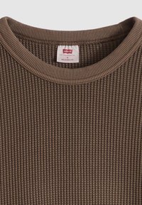 Καφέ μακρυμάνικη ριμπ μπλούζα με στρογγυλή λαιμόκοψη. Φέρει ετικέτα που αναγράφει "Levi's", μέγεθος μεσαίο και "Relaxed Fit". Υφή υφάσματος με ανάγλυφη επιφάνεια.