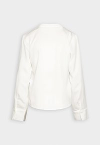 Blusa bianca a maniche lunghe con tessuto liscio e morbido. Presenta un orlo rotondo e polsini con bottoni, con un design semplice e pulito.