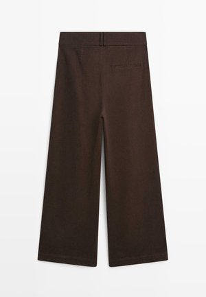 Pantaloni larghi di colore marrone scuro con una tasca posteriori a welt e passanti per cintura, mostrati in piano su uno sfondo bianco.