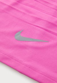 Roze Nike-stof met horizontale textuur; heeft een zilveren swoosh-logo. Glad materiaal en zichtbare stiksels langs de rand.