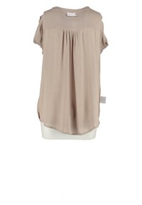 Blouse beige à manches courtes avec plis verticaux dans le dos. Tissu léger, ourlet arrondi, fentes sur les côtés, et une étiquette en bas à gauche.