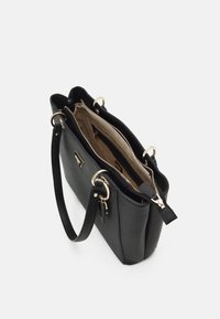 Sort læderhåndtaske med to håndtag og gulddetaljer, åben lynlås afslører beige indre med lynlåslomme og mønstret foer.