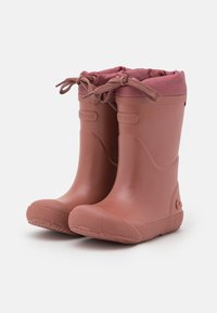 Roze rubberen regenlaarzen met een ronde neus, een getextureerde zool en een trekkoord bij de bovenkant. Glad afgewerkt met een logo-detail aan de zijkant.