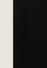 Tela negra con texto en relieve verticalmente a lo largo del lado. Textura suave, diseño simple y sin patrones ni acentos adicionales.