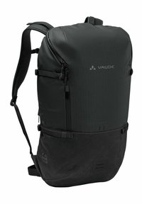 Mochila negra con una superficie texturada, que cuenta con un compartimento principal con cremallera, correas ajustables y una sección inferior reforzada.