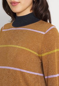 Pull en tricot avec un col roulé côtelé noir. La couleur principale est marron avec des rayures horizontales en violet et jaune. Texture brillante avec des détails en tricot ouvert.