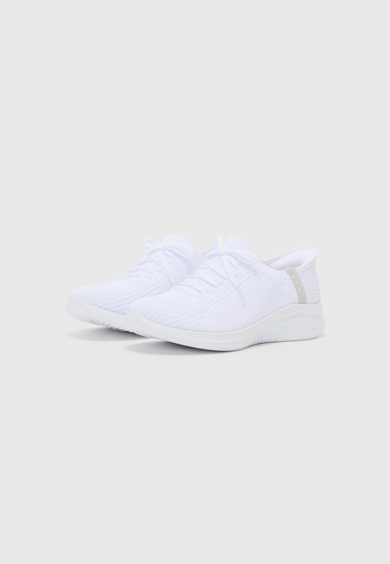 Scarpe da ginnastica bianche con tomaia a maglia traspirante, suola bianca spessa e accento grigio chiaro sul tallone. I lacci sono ben allacciati.