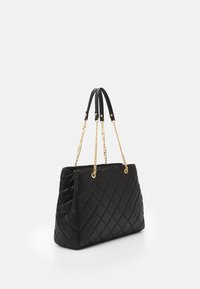 Sac à main en cuir matelassé noir avec une forme structurée, doté de poignées en chaîne dorée et en cuir, et d'une texture lisse.