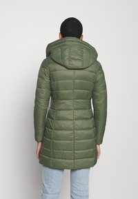 Abrigo acolchado verde con capucha, con diseño acolchado horizontal, mangas largas y longitud a mitad del muslo. Textura suave, con detalles mínimos.