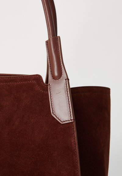 Καφέ σουέτ τσάντα tote με λείο δερμάτινο χερούλι. Διαθέτει καθαρή, δομημένη γραμμή, μαλακή υφή και ελάχιστες ραφές.