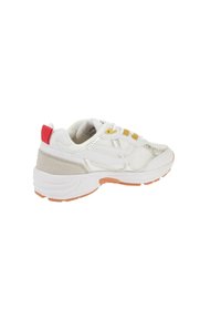 Hvit sneaker med mesh-paneler, sølvdetaljer, gule snøringer og rød hælflik. Har avrundet såle og teksturert overflate.