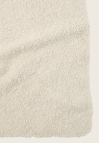Tessuto di colore crema con una superficie testurizzata e soffice. Il design presenta un pelo morbido e leggermente irregolare con una sottile lucentezza.