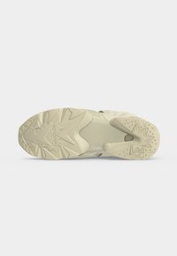 Semelle de basket beige avec motifs en étoile et zigzag en relief et le logo Reebok visible au centre.