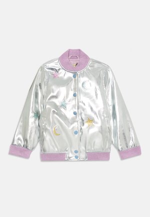 Metallisk sølv bomberjakke med en lilla krage. Har stjerner og halvmåne broderi i rosa, blått og gull. To blå knapper.