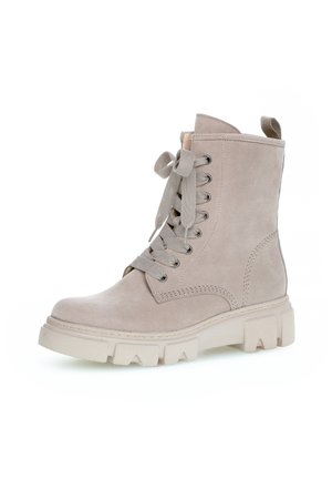 Lichtbeige suède enkelboot met ronde neus, dikke veters, metalen oogjes en een dikke rubberen zool met een gepatternde loop.