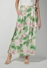 Jupe longue et fluide avec un motif floral pastel aux teintes vertes et roses. Elle dispose d'une taille nouée et de poches latérales. Tissu doux avec une texture légère.