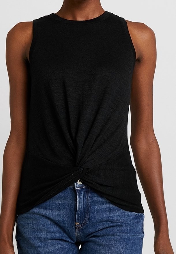 Svart ärmlös topp i ett mjukt, lättviktsmaterial. Har en vriden framsidesdesign med en knuten accent. Matchad med blå denimjeans.