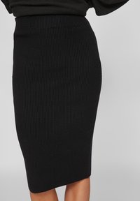Zwarte geribbelde kokerrok, aansluitend ontwerp, knielengte, dikke elastische tailleband, textuurstof, minimalistische stijl, geen zichtbare hardware.