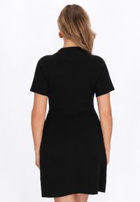 Rochie neagră, ajustată, cu mâneci scurte, decolteu rotund și tiv evazat. Material neted cu o textură subtilă, design personalizat.