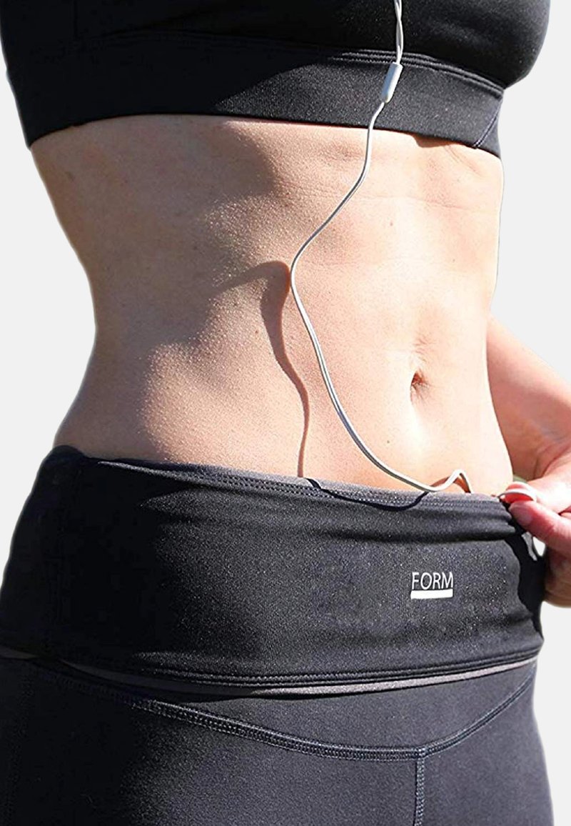 Black athletic crop top with a wide band featuring a "FORM" logo, smooth texture, and an earphone cord visible along the torso.