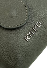 Pelle texturizzata verde scuro con una patta liscia e il logo argento "RYŁKO." Presenta cuciture visibili e un design compatto e arrotondato.