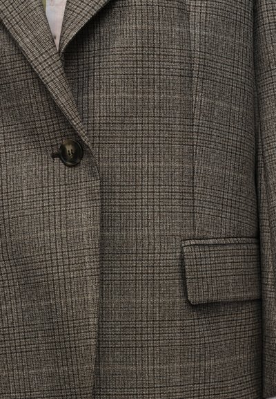 Γκρι και καφέ καρό σακάκι με γιακά με σκισμή, ένα σκούρο κουμπί και ένα τσέπη με καπάκι στη δεξιά μπροστινή πλευρά.