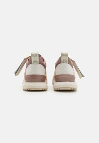 Achteraanzicht van sneakers met een mix van beige, wit en roze materialen, textuurdetails en een logo-blopende trekband.