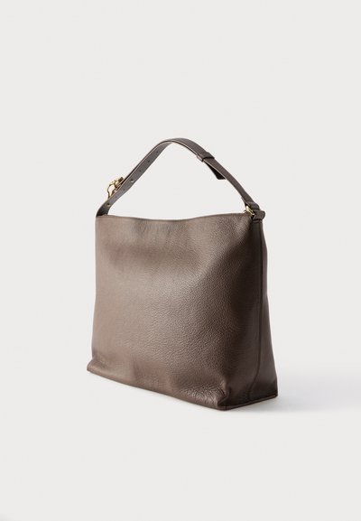 Sac à main en cuir brun texturé avec une bandoulière ajustable unique et une quincaillerie dorée sur fond blanc.