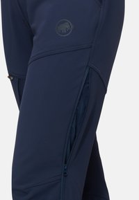 Marina atletiska byxor gjorda av elastiskt tyg, med en sidoficka med dragkedja och en logotyp. Slät textur med skräddarsydda sömmar för en skräddarsydd look.