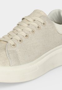 Μπεζ υφασμάτινο αθλητικό παπούτσι με ταιριαστά κορδόνια, μεταλλικές οπές, λευκή μαλακή σόλα και επενδεδυμένο γιακά για άνεση.