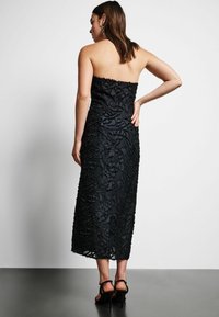 Must mustriline dresses, millee ja pitsdekoorimisega, keskpaiku säärt, kitsas disain ja sirge äärega. Kanda kontsadega sandaalidega.