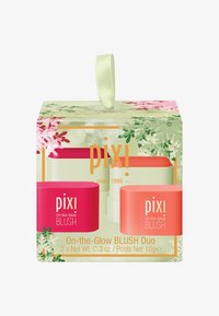 Duo af runde blush-containere i klart pink og koral, pakket i en grøn boks med blomster mønstre og et båndhåndtag, label synlig.