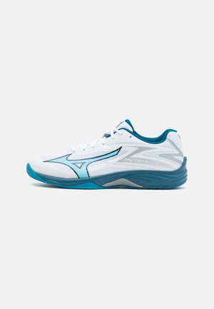 Zapatilla deportiva blanca con acentos en turquesa, que presenta un diseño elegante, parte superior de malla texturizada y una suela curvada para un soporte mejorado.