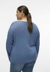 Maglietta a maniche lunghe blu con vestibilità comoda, scollatura rotonda, tessuto morbido e design semplice, abbinata a jeans di denim blu.